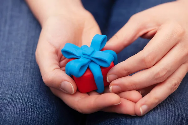 Woman holds gift wrapped with blue ribbon — Stock Photo, Image