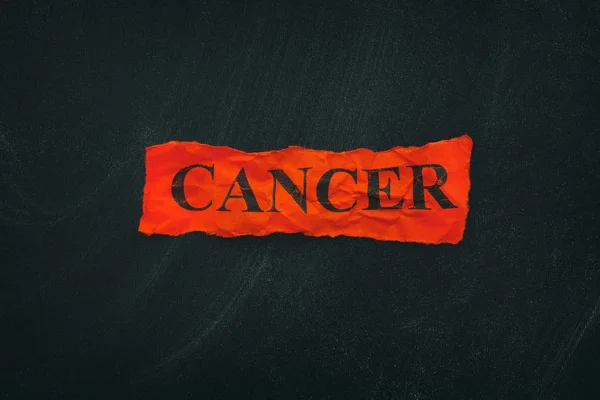 Parola Cancro su un pezzo di carta strappato rosso — Foto Stock