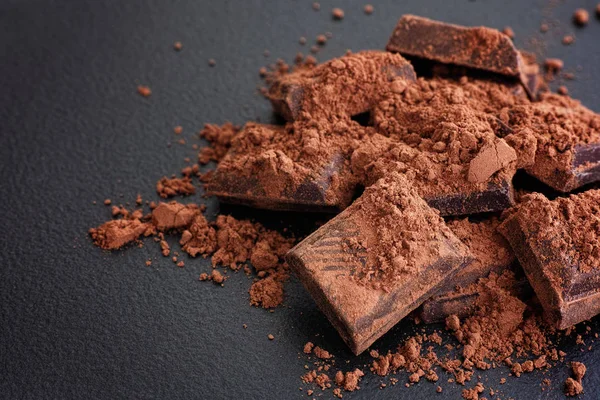 Gebrochene dunkle Schokolade mit Kakaopulver — Stockfoto