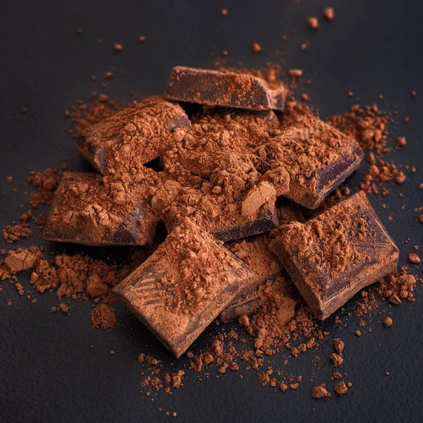Broken dark chocolate with cocoa powder — Stock Photo, Image