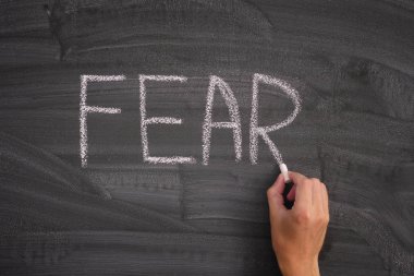 Kişi bir tahta üzerinde Fear sözcüğü yazma