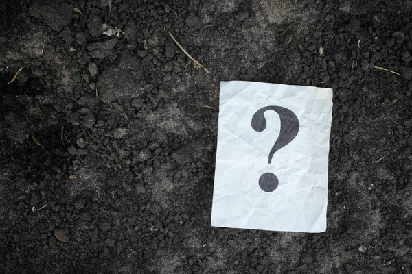 Nota di carta con punto interrogativo sullo sfondo del suolo — Foto Stock