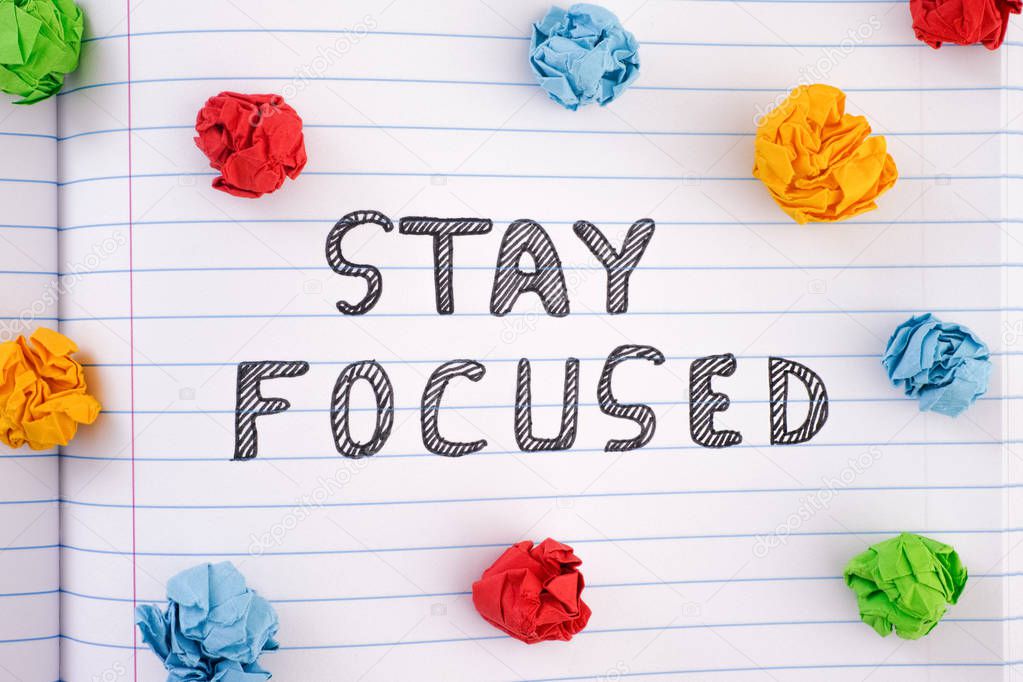 Phrase Stay Focused on notebook sheet with some colorful crumple