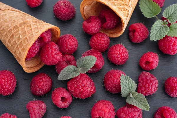 Raspberries and mint leaves spilling out of ice cream cones — Stock Photo, Image