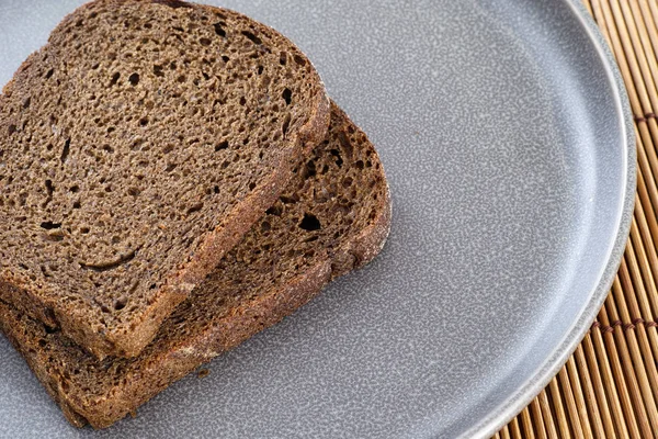 Slices of whole grain organic bread on a gray plate — Stock Photo, Image