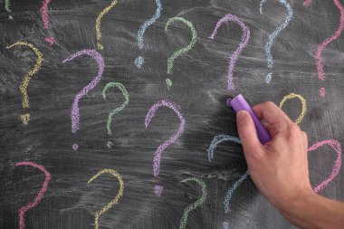 Tahtaya renkli soru işaretleri çizen adam