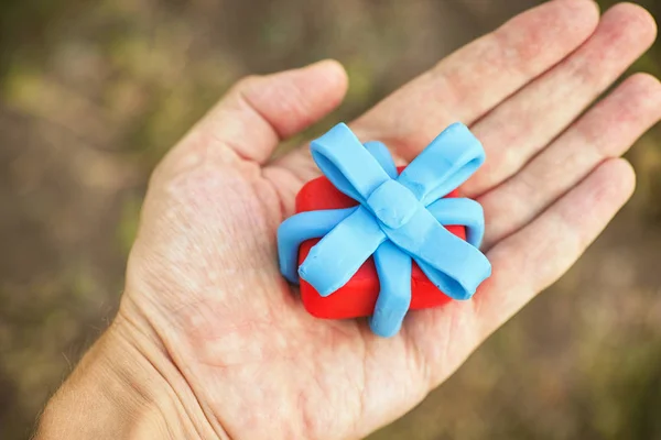 Person holding gift wrapped with blue ribbon — Stock fotografie