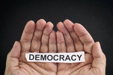 Elinde Demokrasi yazan bir kağıt parçası tutan adam. Kapat..