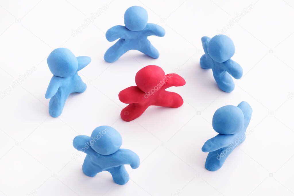 Blue plasticine people surrounding red plasticine person. Stand out from the crowd. Bullying concept. Close up.