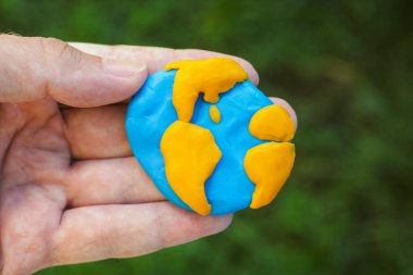 Man holding planet Earth in his hand. Planet Earth is made out of play clay (plasticine). clipart