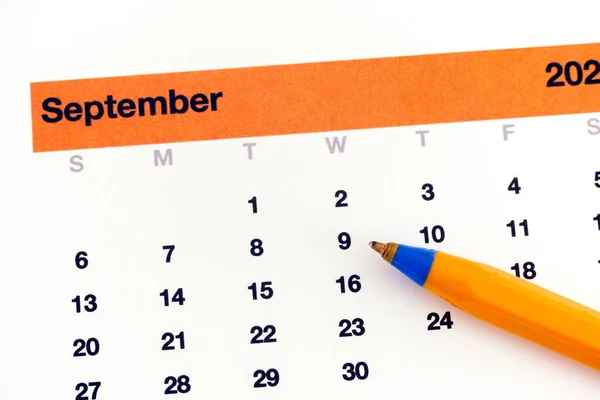 一支圆珠笔躺在显示九月的日历上 靠近点 — 图库照片