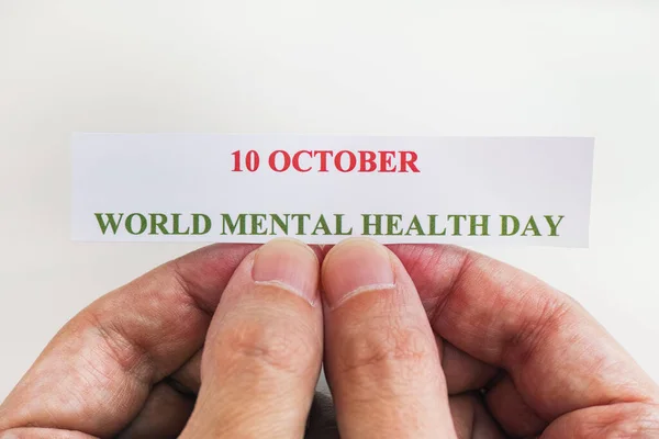 Person holding piece of paper with the words World Mental Health Day (10 October). Close up.