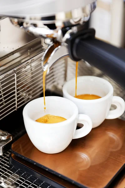 Coffee brewing in coffee machine. Espresso pouring in two cups.