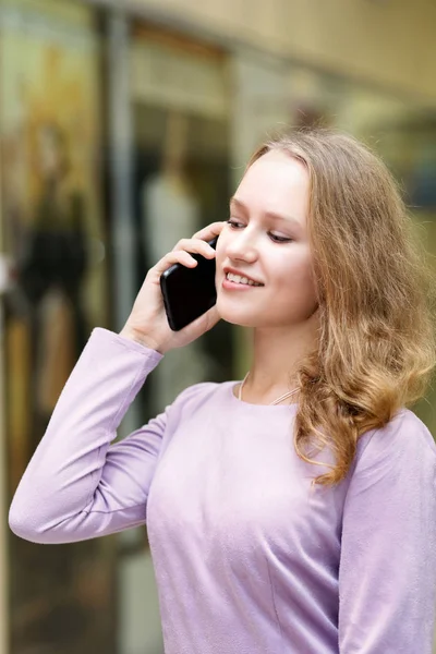 Portrait of young girl who talking by mobile phone. Shallow focus and blurred background.