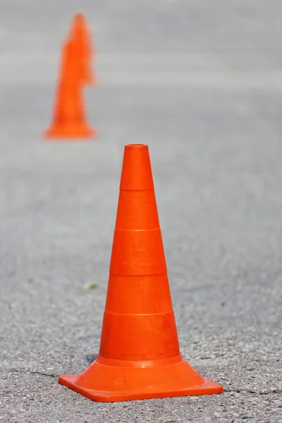 Orange plastic traffic cones on asphalt. Shallow focus.