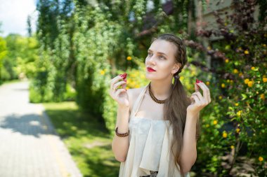 Güzel kız. Profesyonel makyaj, kavramsal fikir. Bej deri. Canlı renkler, yeşil çalılar park. Kozmetik ruj, renkli mücevher jevelry, bilezik kolye. yakın çekim fotoğraf. mükemmel ince gövde