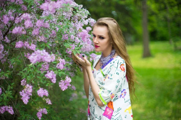 美丽的女孩在春天的花园里站在盛开的开花树附近 年轻女子穿着时尚礼服在公园附近的灌木丛开花 气味芳香的性质 水平图片横幅自由地方 — 图库照片