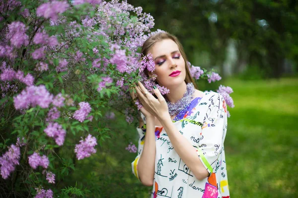 美丽的女孩在春天的花园里站在盛开的开花树附近 年轻女子穿着时尚礼服在公园附近的灌木丛开花 气味芳香的性质 水平图片横幅自由地方 — 图库照片