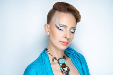 Seksi kız yüz portre portre. Kısa yaratıcı saç kesimi, Traşlı Tapınağı, kadınla altın sprey boyalı. Turuncu saç boyası. Mavi boncuk p.kodu rhinestones büyük takılar kolye yapılmış