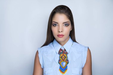 Genç güzel kız mavi kot bluz koyar. Büyük kolye renkli etnik sembolleri. Geleneksel süsler nakış. Turuncu sarı kırmızı boncuklar. Profesyonel makyaj kalem tekniği kırışık kesilmiş.