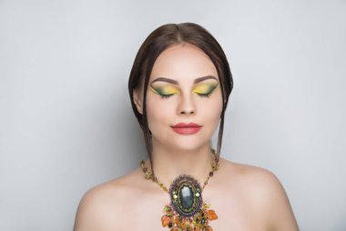 Genç güzel kız büyük kolye takmış. Sihirli el yapımı takılar. Seksi çıplak omuz. Uzun kirpiklere, yeni parlak ruj dudakları parlak, el yapımı mücevher taşları ortağı giyiyor. Mükemmel yüz fotoğraf