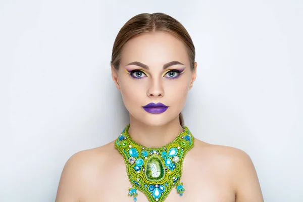 New creative make-up, conceptual art idea. eyeshadows, vivid colors graphic shapes lines, cosmetics paints, necklace jewellery. close-up photo. skin painting artistic. perfect straight lines on eyes