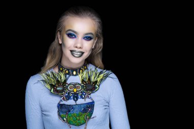 Yeşil orman kadın sanat makyaj. Komik resim bir Cadılar Bayramı partisi afiş için. Yaratıcı makyaj, büyük boncuk demir kolye. Gerdanlık baykuş gözleri iri ve kabarık tüyleri ile. Mavi parlak parlak gölgeler