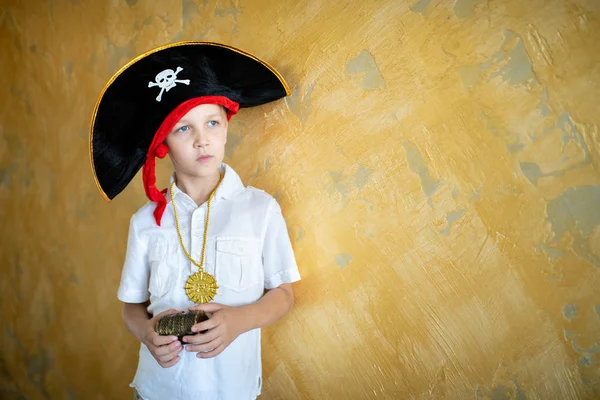 Boy pirate preparing for the holiday Halloween. Big pirate hat captain of a ship, male role play at a costume party children's holiday. Fun and emotions for a good mood. Studio wall horizontal banner