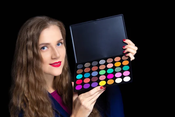 Young beautiful girl holding plastic palette with a multi-colored shadows. Bright colors to create customer ideas. Ready to work make-up artist at party or saloon. In the hand of professional tools