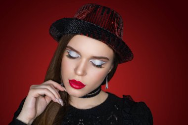 Güzel bir kadın portreyi kapatır. Profesyonel makyaj, beyaz göz farı, uzun kirpikleri, yeni kırmızı ruj. Zarif saç stili, büyük aksesuar boğucu. Yatay pankart, gradyan arkaplan