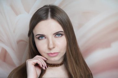 Kahverengi makyajlı, dumanlı gözlü güzel bir kadın. Uzun düz saçlar, toplanmış saçlar. Profesyonel makyaj, çıplak mat dudaklar, su geçirmez ruj. Rüya gibi mavi gözler, parmaklarıyla çenesine dokunuyor.