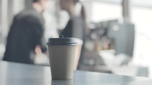 A glass of hot coffee is on the bar. Baristo in the background make coffee. Blurred background. — Stock Video