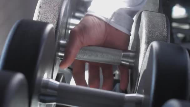 De hand van een getrainde atleet neemt een zware halter. — Stockvideo
