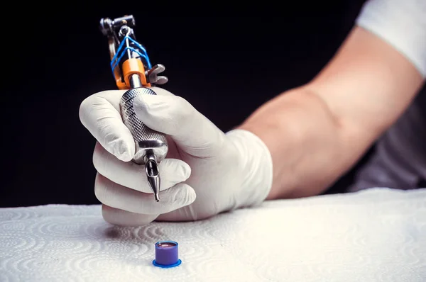 Mão de um mestre de tatuagem com uma arma de tatuagem . — Fotografia de Stock