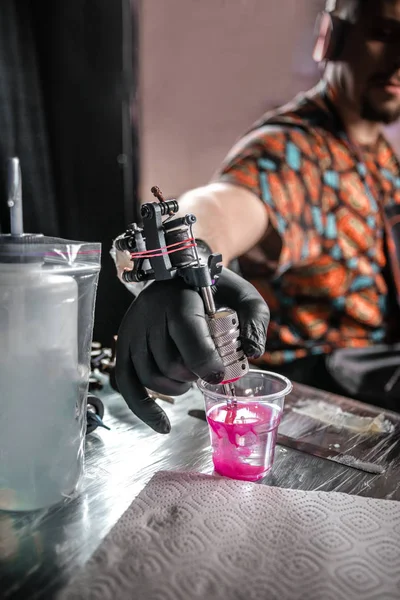 Tatueringskonstnärens hand med tatueringsmaskin. — Stockfoto