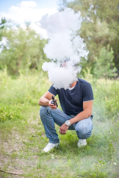 Adam alanında e-sigara doğa üzerinde çizgili yelek — Stok fotoğraf