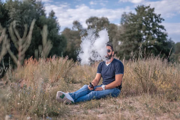 Ritratto uomo vaporizzando all'aperto espira nube di fumo — Foto Stock