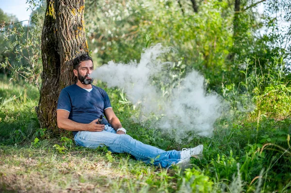 Stylish brutal man blows up a couple an vape. Electronic cigarette as alternative to tobacco.