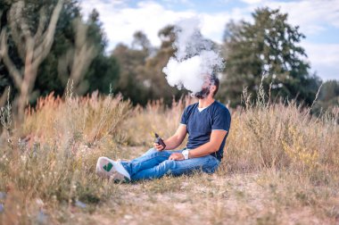 Kendine güvenen vape adam ormanda elektronik sigara keyfi. Sigaraya alternatif.