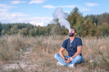 Acımasız vape adam tutun ve duman bir akış üfleme onun elektronik duman cihazı yayıldı. Şık adam.