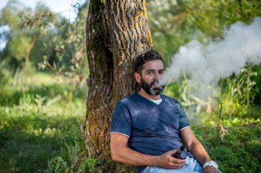 Şık acımasız adam bir elektronik sigara outdoorr sigara. Sigara içilmeyen.