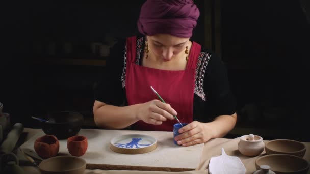 Girl in traditional national dress paints pottery — Stock Video