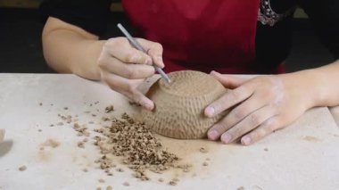 Pottery. Female ceramist apply texture to freshly prepared ceramic ware.