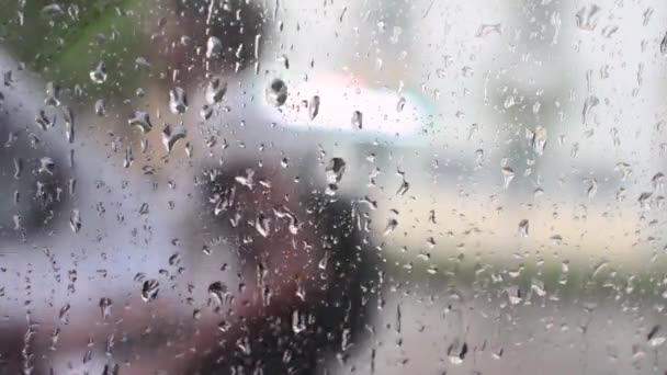 Pluie. Des gouttes de pluie sur le verre. Un homme et une femme se cachant de la pluie . — Video