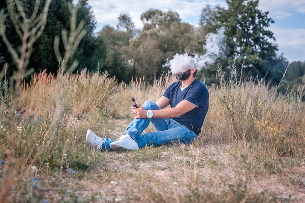 Un uomo sicuro di se 'fa saltare in aria un paio di sigarette elettroniche. Sigaretta elettronica in alternativa al tabacco . — Foto Stock