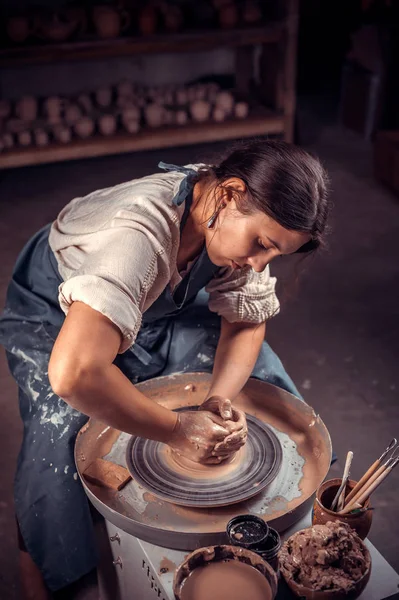 Charmante ambachtelijke vrouw creëert een nieuw aardewerk van klei op een Potters wiel. Folk handwerk. — Stockfoto