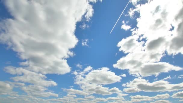 Літак летить у блакитному небі серед хмар і сонячного світла — стокове відео