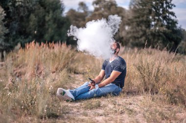 Sakallı sigara içen doğada vape elektronik sigara kullanarak duman çok üfleme. Elektronik sigara.
