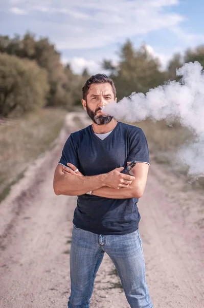 Modern sigara tiryakisi ormanda elektronik sigara içiyor. Sigara bırakma tütünü. — Stok fotoğraf