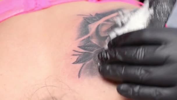 Tatuaje artista rellena un tatuaje en el hombro de una mujer. Primer plano . — Vídeo de stock